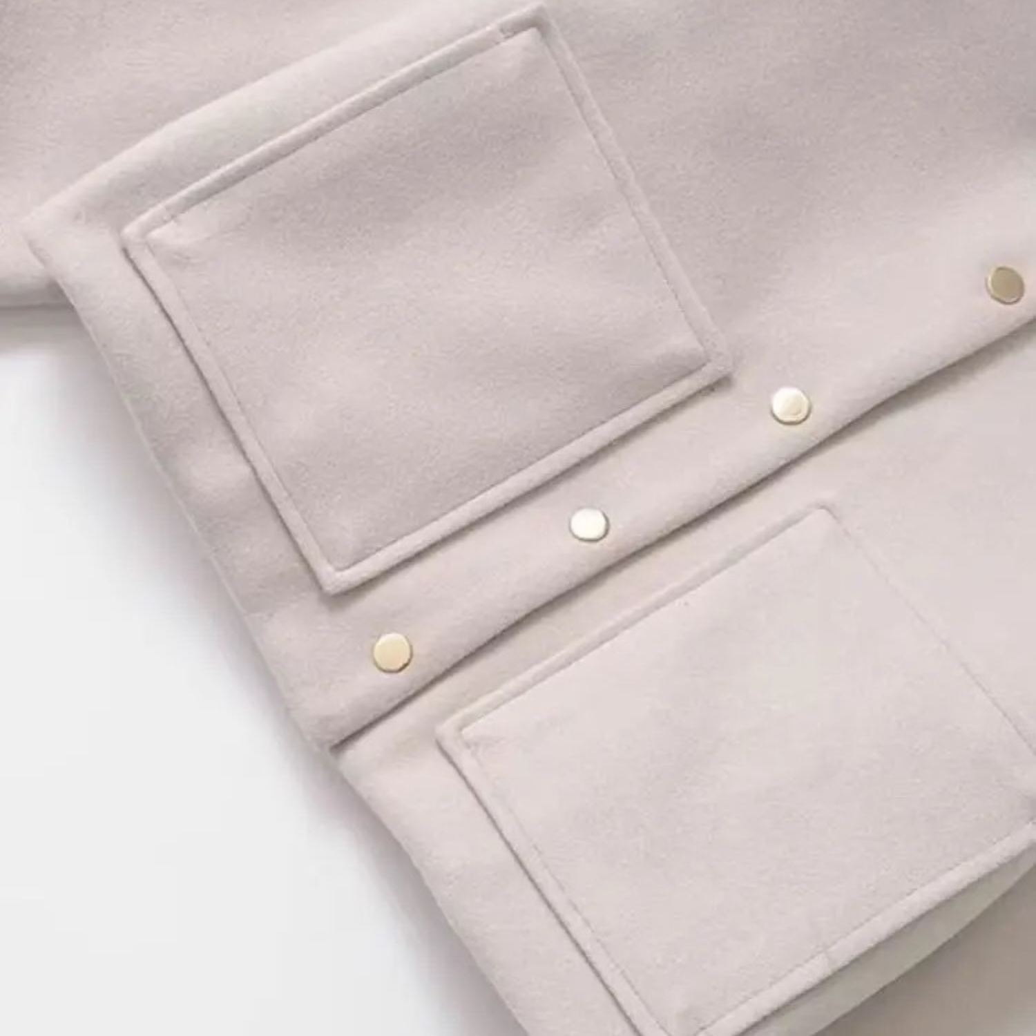 Beige jacket with square pockets and gold buttons.
