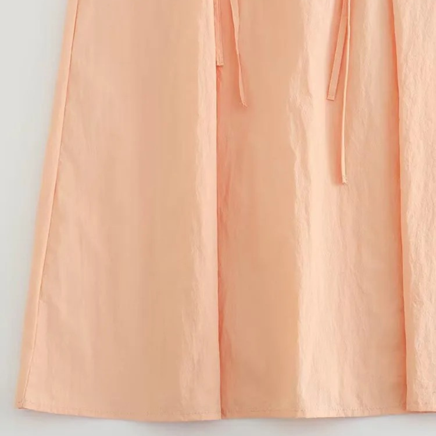 Peach-colored fabric with drawstring.