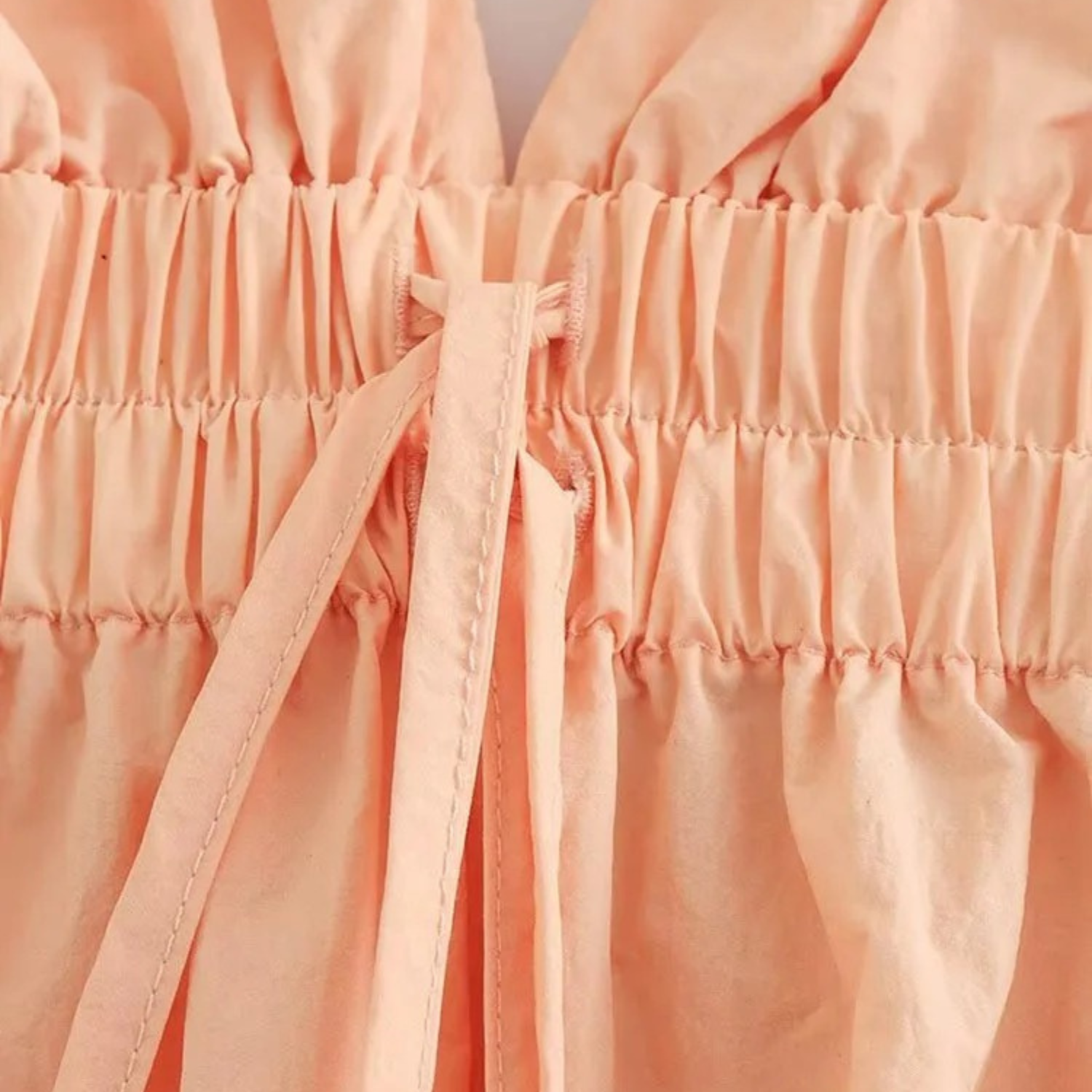 Peach-colored gathered fabric with tie.